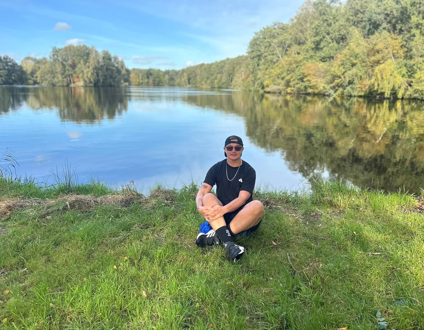Ethan zit ontspannen in het gras bij het meer